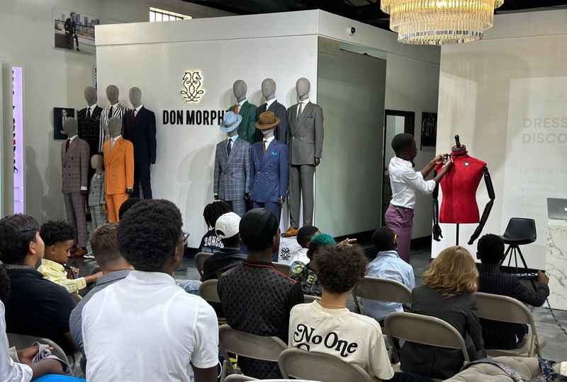 A presenter demonstrates styling on a dress form at the Don Morphy showroom during a Threads for Change event