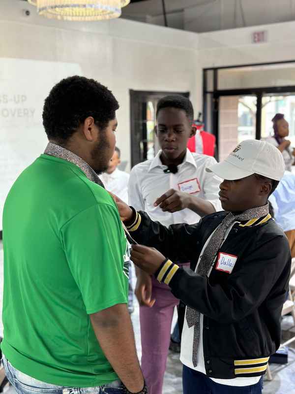 Workshop participants helping each other practice tie tying