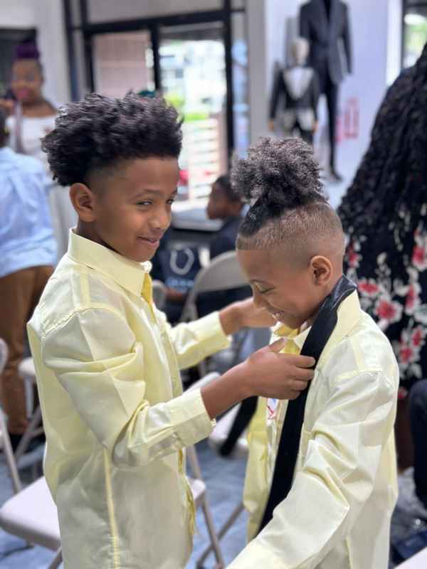 Two smiling boys practicing tie tying during the workshop