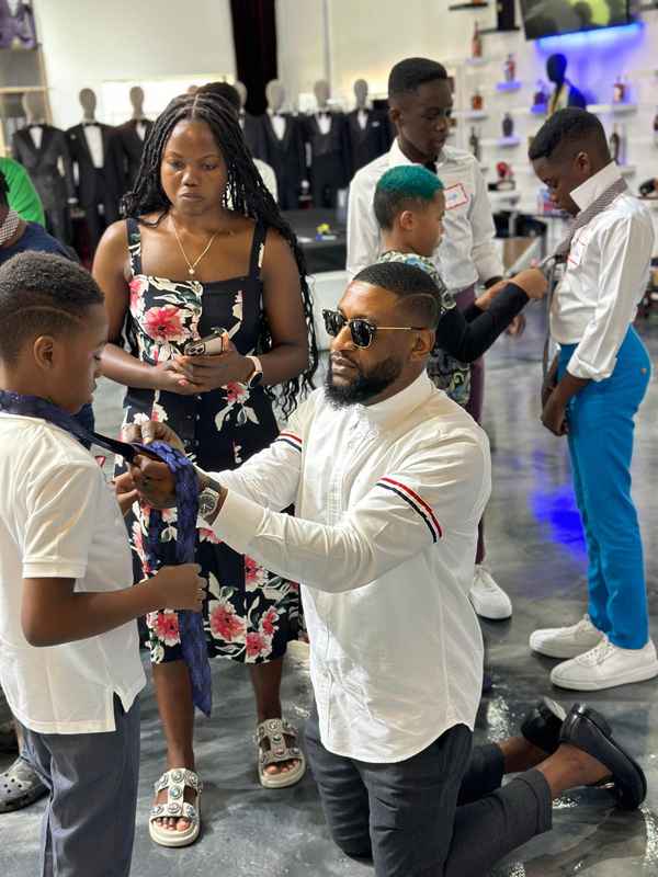 A volunteer kneeling to tie a bow tie for a young participant